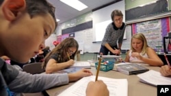 FILE - Teacher Joy Burke checks on the work of her fifth grade students at John Hay Elementary school in Seattle. 