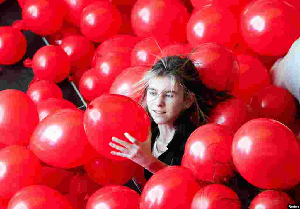 A girl is surrounded by balloons during Valentine&#39;s Day celebrations at the Riviera shopping mall in Moscow, Russia.