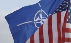 FILE - A NATO and a US flag flutter in the wind outside NATO headquarters in Brussels.