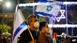 Para pengunjuk rasa mengenakan masker untuk melindung penularan virus corona di tengah unjuk rasa anti-pemerintah di lapangan Rabin, Tel Aviv, Israel, Sabtu, 2 Mei 2020. (Foto: AP)