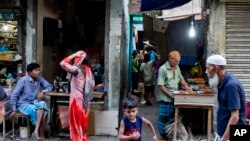 Bangladesh Anti-drugs CrackdownResidents walk past a man making barbecue in an alley at the Mohammadpur Geneva camp, where over 100 suspected drug peddlers detained in a raid by Rapid Action Battalion (RAB) in Dhaka, Bangladesh, Saturday, May 26, 2018.