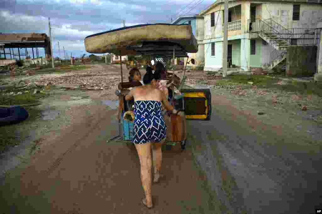 زن کوبایی در حال هل دادن سه چرخه شوهرش،&nbsp; که حامل وسایل قابل استفاده و باقی مانده از خانه شان بعد از توفان ایرماست.