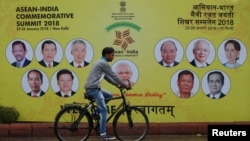 A cyclist rides past an ASEAN-India Commemorative Summit billboard on the side of the road in New Delhi, India, Jan. 23, 2018. 