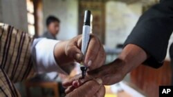 Bhutanese polling official puts indelible ink mark on voter's finger after she casts vote in nation's second parliamentary, Rikhey, April 23, 2013.