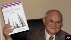 FILE - Chairman of the Constitution Drafting Commission Meechai Ruchupan holds the draft of new constitution during a press conference at the Parliament in Bangkok, Thailand, March 29, 2016.