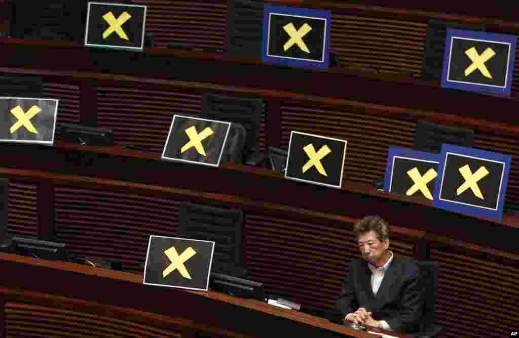 Pro-democracy lawmaker Ronny Tong sits with placards of yellow crosses placed after lawmakers walked out of the legislative chamber to protest against Chief Secretary Carrie Lam who unveiled a Beijing-backed election reform package’s details, in Hong Kong.