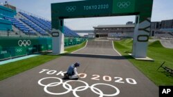 A worker paints Olympic rings at the finish line of the BMX racing track as preparations continue for the 2020 Summer Olympics, Tuesday, July 20, 2021, at the Ariake Urban Sports Park in Tokyo. (AP Photo/Charlie Riedel)