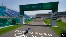 A worker paints Olympic rings at the finish line of the BMX racing track as preparations continue for the 2020 Summer Olympics, Tuesday, July 20, 2021, at the Ariake Urban Sports Park in Tokyo. (AP Photo/Charlie Riedel)