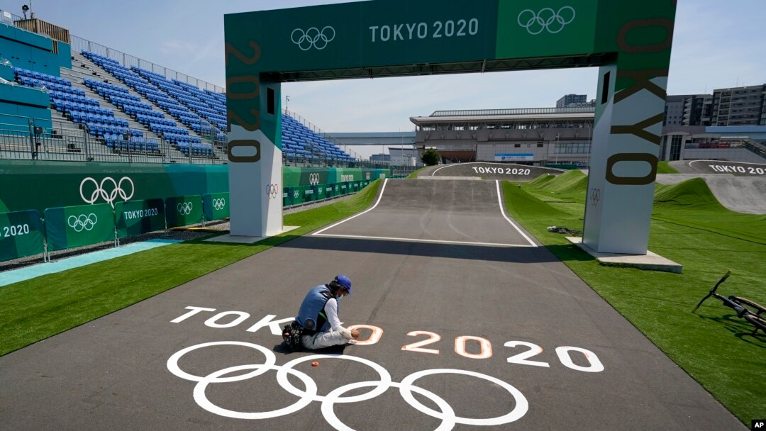 A worker paints Olympic rings at the finish line of the BMX racing track as preparations continue for the 2020 Summer Olympics, Tuesday, July 20, 2021, at the Ariake Urban Sports Park in Tokyo. (AP Photo/Charlie Riedel)