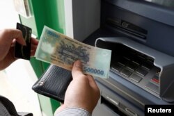 FILE - A man withdraws money from an ATM at a branch of Vietnam Prosperity Joint Stock Commercial Bank (VPBank) in Hanoi, Nov. 15, 2017.