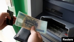 FILE - A man withdraws money from an ATM at a branch of Vietnam Prosperity Joint Stock Commercial Bank (VPBank) in Hanoi, Nov. 15, 2017. 