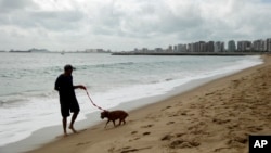 A man walks his dog on the beach during the 2014 soccer World Cup in Fotaleza, Brazil, June 17, 2014. 