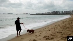 A man walks his dog on the beach during the 2014 soccer World Cup in Fotaleza, Brazil, June 17, 2014. 