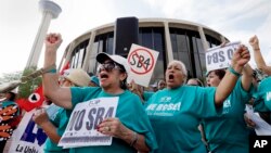 FILE - Lydia Balderas, left, and Merced Leyua, right, join others as they protest against a new sanctuary cities bill outside the federal courthouse in San Antonio, June 26, 2017.