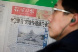 FILE - A man stands in front of a copy of the Global Times newspaper featuring an image of the U.S. Capitol during preparation for the inauguration of Joe Biden as the U.S. president, in a window in Beijing, China, Jan. 21, 2021.