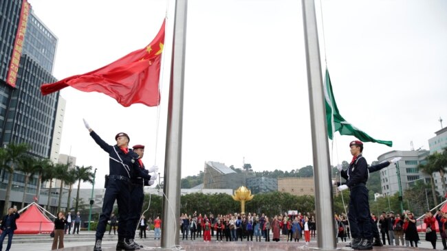 澳门警察在金莲花广场升起中国国旗和澳门特区旗帜。（2019年12月19日）