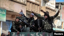 Fighters of the Kurdish People's Protection Units (YPG) carry their weapons along a street in the Syrian Kurdish city of Qamishli, in celebration after it was reported that Kurdish forces took control of the Syrian town of Tel Hamis, Feb. 27, 2015. 