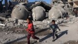 دو فلسطیی بچے غزہ کی پٹی میں واقع رفح کے پناہ گزین کیمپ پر اسرائیلی بمباری سے منہدم مسجد اور رہائشی عمارتوں کے ملبے کے پاس سے گزر رہے ہیں۔ 22 فروری 2024