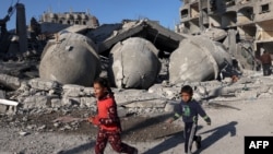 FILE - Palestinian children walk past the rubble of the al-Faruq mosque on February 22, 2024, following an overnight Israeli air strike in Rafah refugee camp in the southern Gaza Strip.