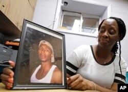 Veronica Parker holds a photo of her son, Korey B. Parker, Sr., 27, at her workplace in Chicago, Nov. 9, 2018. He was fatally shot around the corner from her house on July 4, 2012. The killing remains unsolved.