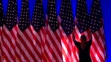 Un trabajador ajusta las banderas en el escenario antes de un evento en el comando de campaña del candidato presidencial republicano Donald Trump, en West Palm Beach, Florida, el 5 de noviembre de 2024.