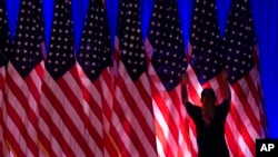 Un trabajador ajusta las banderas en el escenario antes de un evento en el comando de campaña del candidato presidencial republicano Donald Trump, en West Palm Beach, Florida, el 5 de noviembre de 2024.