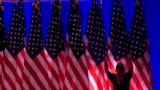 A worker adjusts the flags on stage ahead of an election night watch party for Republican presidential nominee former President Donald Trump in West Palm Beach, Fla., Nov. 5, 2024.