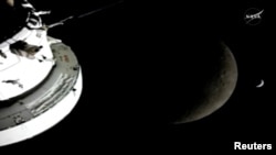 “阿尔忒弥斯二号”任务的“猎户座”飞行船即将抵达距离地球最远地点之际，看到月球和地球排成一线的景观。照片翻拍自当时直播的视频。NASA/Handout via REUTERS （2026年4月6日）