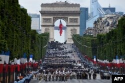 FILE - Troops wait near the Arc de Triomphe, in Paris, before taking part in the annual Bastille Day military parade on the Champs-Elysees avenue on July 14, 2016.