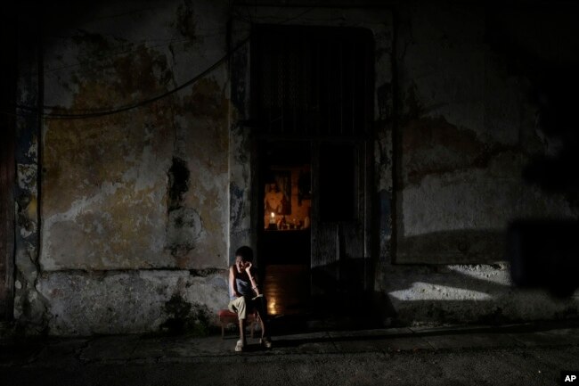 Seorang warga duduk sambil menghabiskan waktu saat listrik padam di Havana, Kuba, 19 Oktober 2024. (Foto: AP)