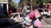 FILE - A man carrying his belongings looks at wreckages of vehicles burnt by armed gangs as he flees the Poste Marchand suburb, in Port-au-Prince, Haiti, Dec. 9, 2024.