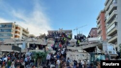 Locals and officials search for survivors at a collapsed building after a strong earthquake struck the Aegean Sea on Friday and was felt in both Greece and Turkey, where some buildings collapsed in the coastal province of Izmir, Turkey, Oct. 30, 2020.