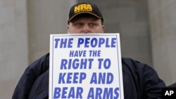 FILE - John Doll, of Renton, Wash., holds a sign that reads "The people have the right to keep and bear arms" during a gun rights rally at the Capitol in Olympia, Wash.