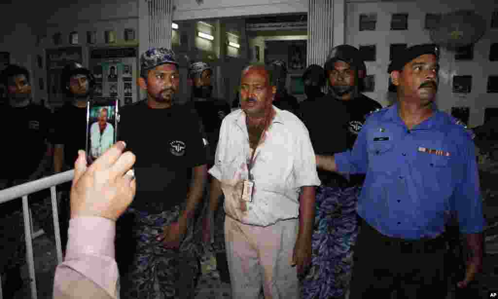 Airport security staff help an injured airline employee, center, leave a terminal following attacks by gunmen at the Jinnah International Airport in Karachi, Pakistan, June 9, 2014.