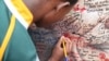A young boy tried to squeeze his name onto a Mandela poster outside his home in Soweto, South Africa. (Hannah McNeish for VOA)