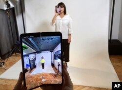 Seorang model memegang ponsel pintar Samsung Galaxy Fold ke arah wajahnya dalam acara untuk media di London, 16 April 2019.