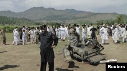 Seorang anggota pasukan keamanan dan penduduk setempat memeriksa lokasi ledakan bom pinggir jalan di daerah kesukuan Dir Bawah di Pakistan, dekat perbatasan Afghanistan (16/9). 