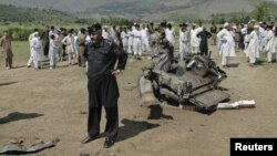 A security official and residents inspect the site of a bomb attack in the Lower Dir tribal area in Pakistan September 16, 2012. 