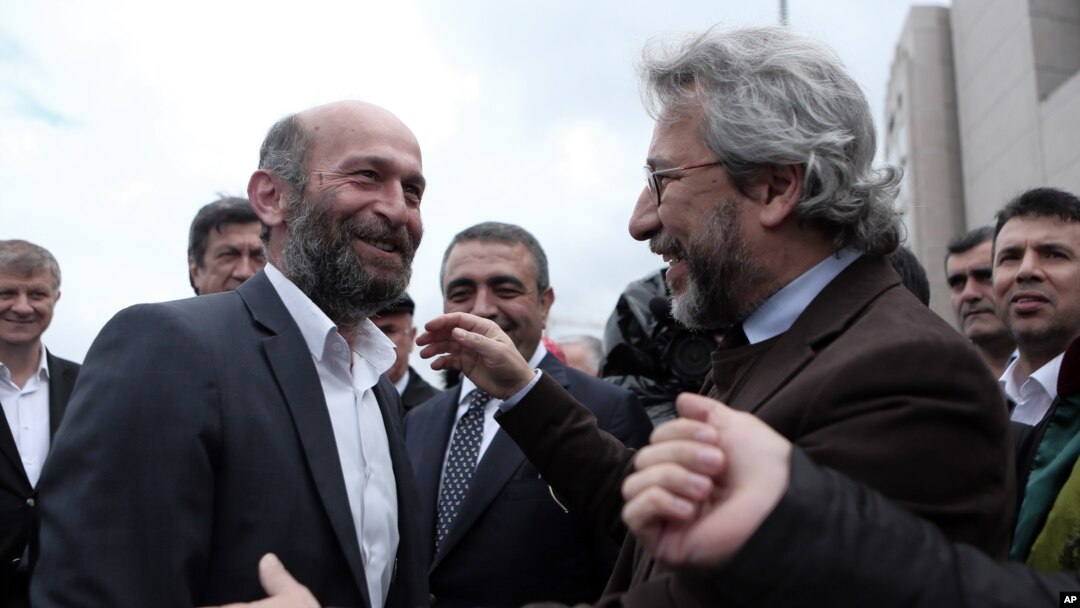 Jurnalis Can Dundar (kanan) dan Erdem Gul, kepala biro Ankara untuk koran Cumhuriyet, berbicara sebelum persidangan dan serangan terhadap Can Dundar di luar gedung pengadilan di Istanbul (6/5). 