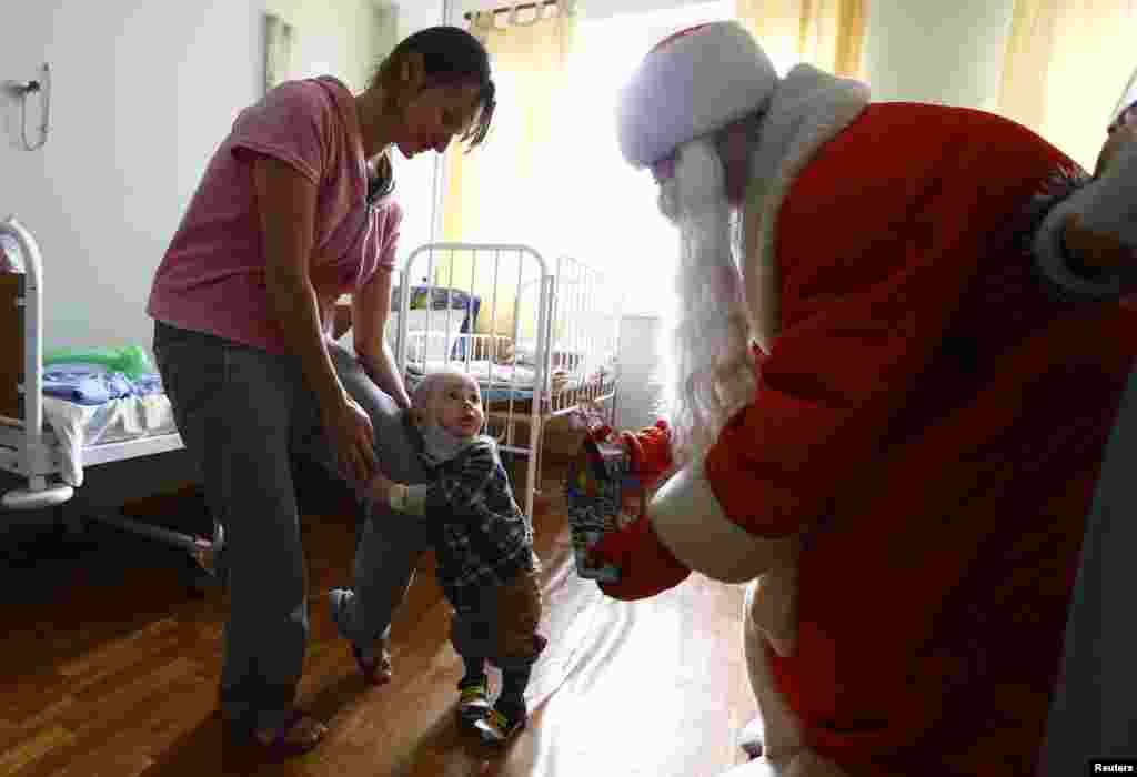 A man dressed as Father Frost, equivalent of Santa Claus, gives a present to a boy on the eve of Christmas in a burn unit of a hospital in Minsk, Belarus.
