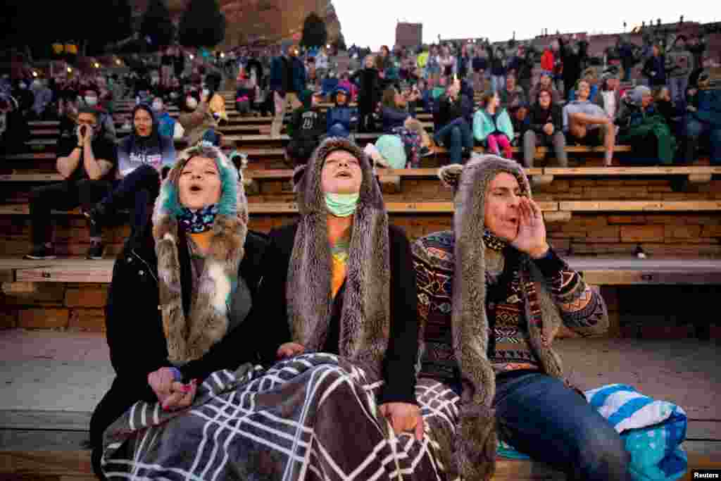 Anita Rose, Jim Galbreath and Dan Galbreath, participate in the &quot;8 o&#39;clock Howl&quot; to honor essential workers at the 80th anniversary season kickoff at the Red Rocks Amphitheatre in Morrison, Colorado, April 28, 2021.