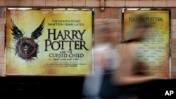 Pedestrians pass a poster advertising the new Harry Potter play at the Palace Theatre in London. 