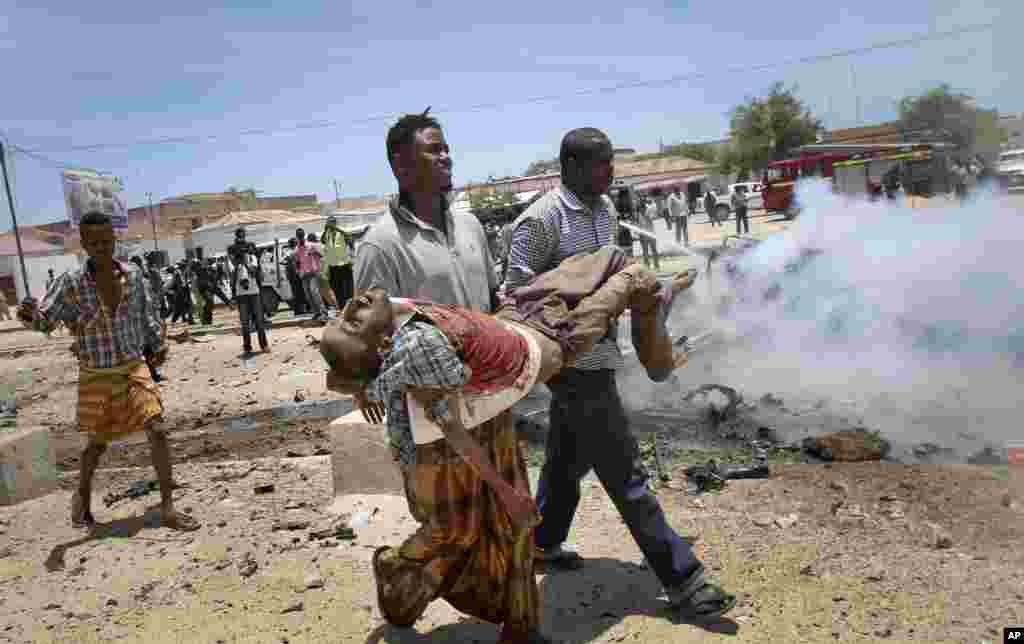 Men carry a seriously wounded man after an explosion in Mogadishu, Somalia, March 18, 2013.