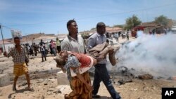 Deux hommes transportent une personne gravement blessée dans l'explosion du 18 mars à Mogadiscio.
