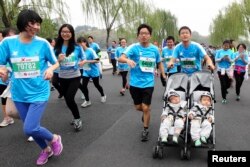 A man pushes a stroller carrying his 13-month-old twins as he runs the Hangzhou International Marathon, in Hangzhou, Zhejiang province, Nov. 2, 2014.