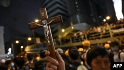 FILE - A protester holds a Christian cross as others gather outside the police headquarters in Hong Kong, June 21, 2019.