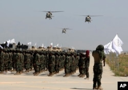 FILE - UH-60 Black Hawk helicopters fly during a military parade to mark the third anniversary of the withdrawal of U.S.-led troops from Afghanistan, in Bagram Air Base in the Parwan Province of Afghanistan, Aug. 14, 2024.