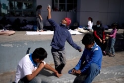 A migrant boy launches a paper airplane while playing with other migrant kids near the McAllen-Hidalgo International Bridge point of entry into the US, after being caught trying to sneak into the US and deported, March 18, 2021, in Reynosa, Mexico.