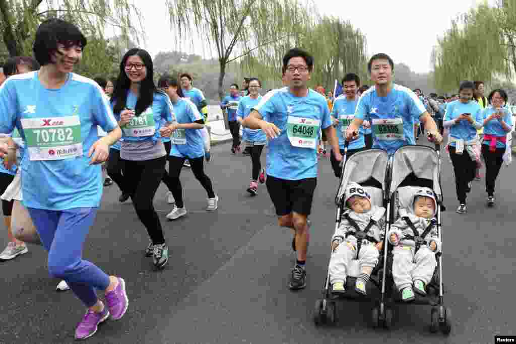 在中国浙江省杭州市举办国际马拉松赛时，一名男子推着婴儿车跑步，车上有13个月大的双胞胎婴儿（2014年11月2日）。