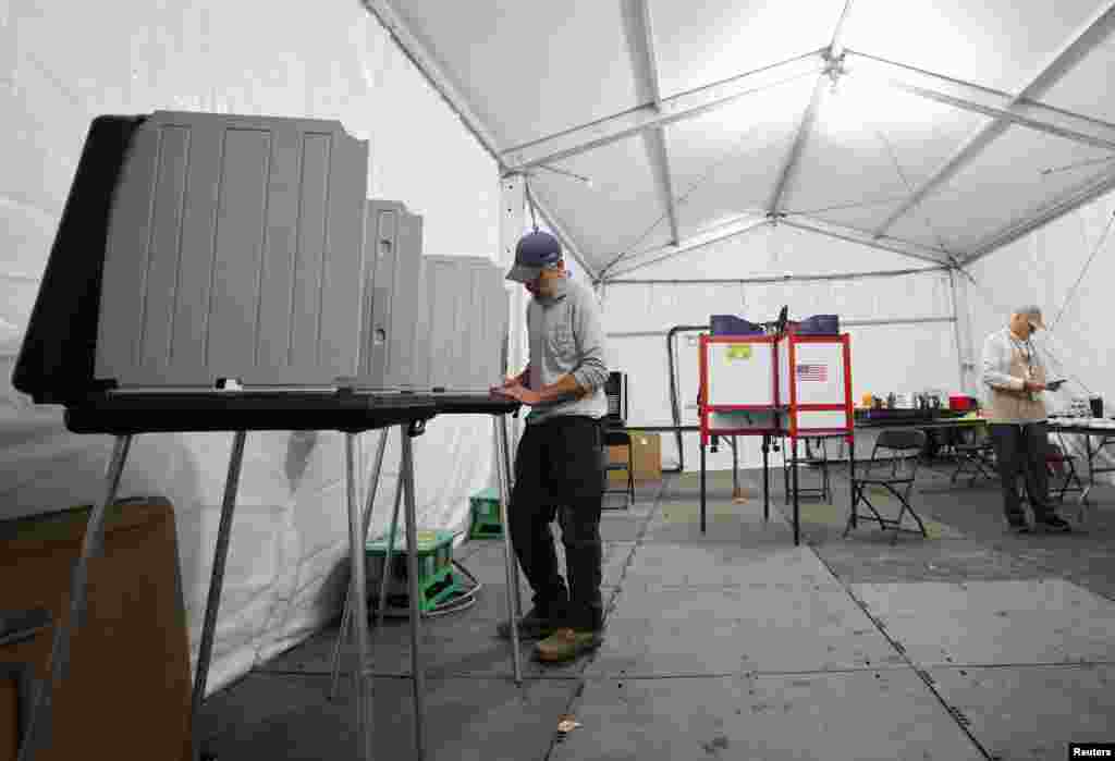 Un hombre vota en un sitio de votación temporal ubicado en una tienda de campaña debido a los daños causados ​​por el huracán Helene, en Black Mountain, Carolina del Norte.